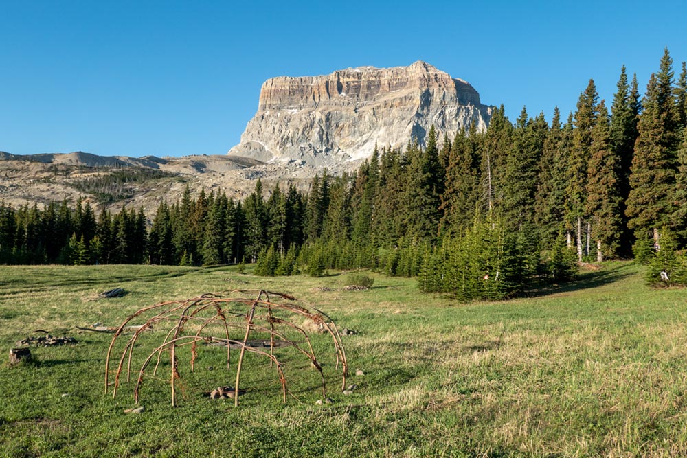 Native American sweat lodge wooden frame and Chief Mountain, Montana