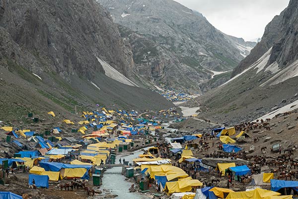 Pyhiinvaeltajien teltat lähellä Amarnath Shiva Cave Temple, luola etäisyydellä valokuvan yläosassa