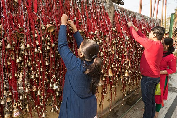 Pilger, die Glocken am Tilinga Mandir Tempel hängen