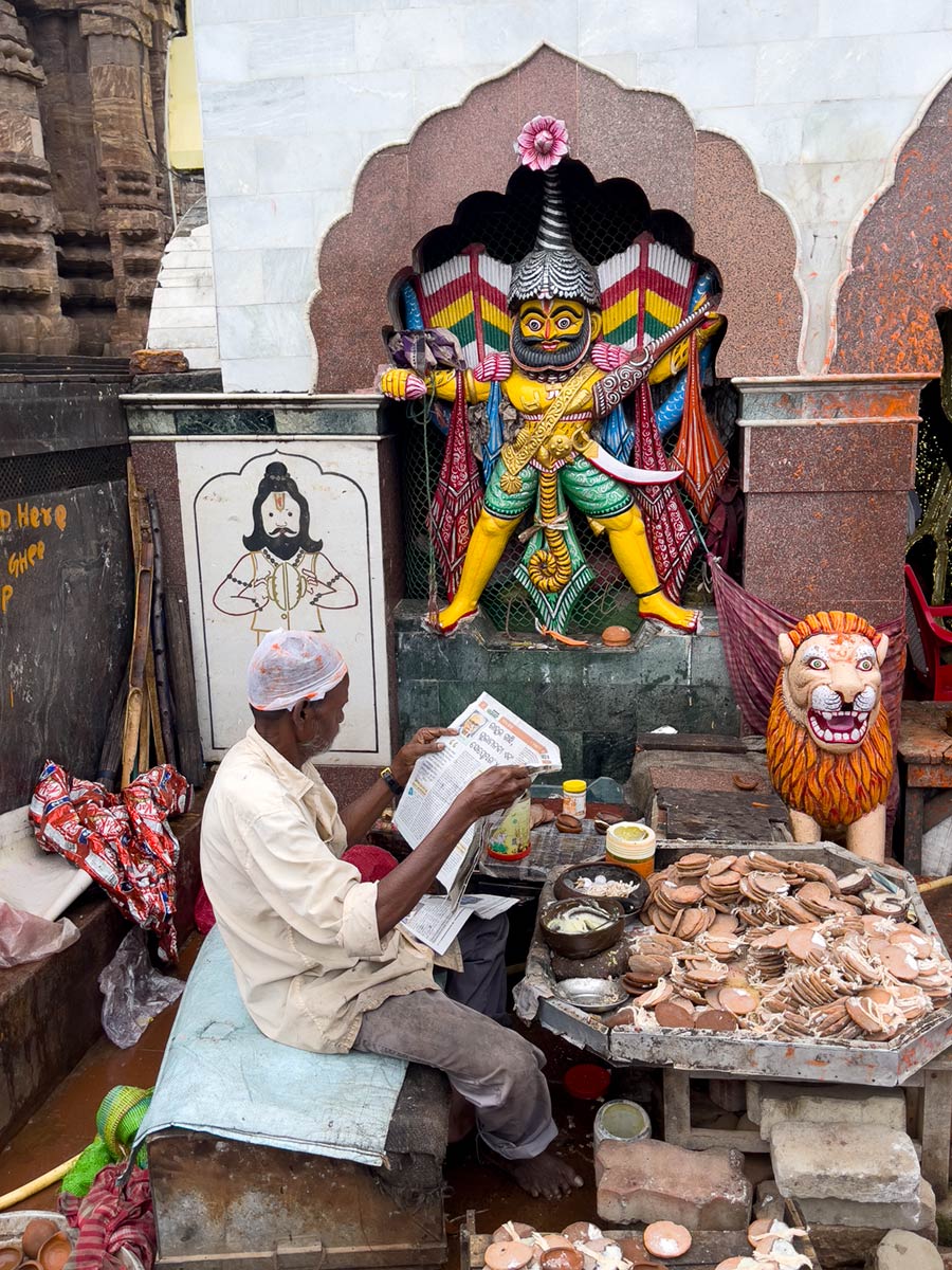 Kerzenverkäufer lesen Zeitung am Eingang zum Jagannath-Tempel, Puri