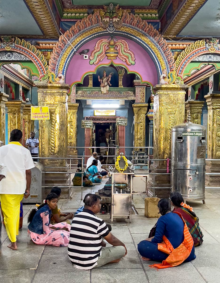 Kumbeshwara Shivan temppeli, Kumbakonam. Pyhiinvaeltajat istuvat lähellä sisäänkäyntiä temppelin sisäiseen pyhäkköön.