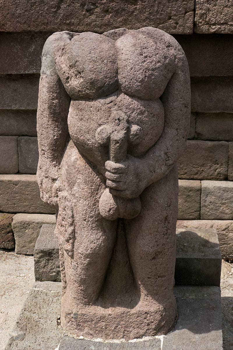 Estatua de piedra con un hombre sosteniendo su pene erecto, Candi Sukuh