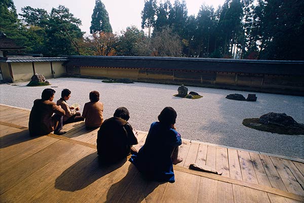 Peregrinos que meditan en el jardín Zen de Ryoan-ji, Kioto, Japón.