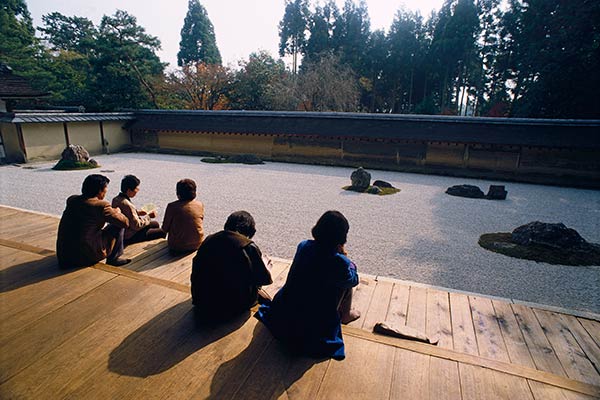 Peregrinos que meditam no jardim do zen de Ryoan-ji, Kyoto, Japão.