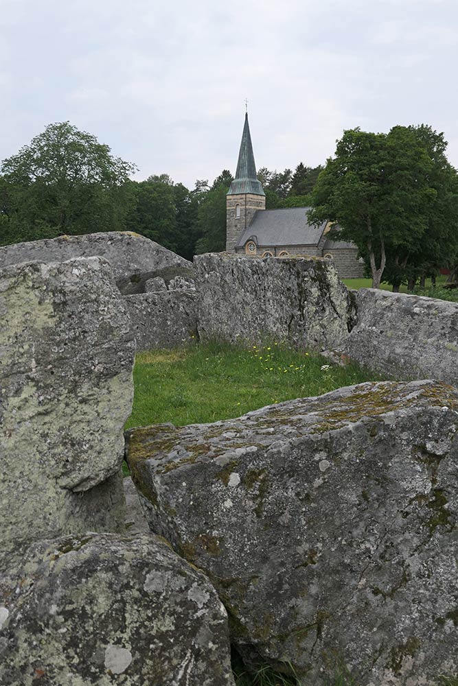 Jättakullen Hällkista Megalith Dolmen mit Kirche im Hintergrund